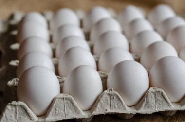 Tepside beyaz tavuk yumurtası var. Birkaç düzine çiğ yumurta. Seçici odaklanma. Kimse yok..