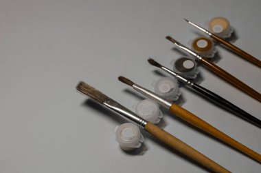 Boya kapları ve boya fırçaları gri arka planda. Sanatçı Yeteneği. Ev yapımı boş zaman. Seçici Odaklanma.