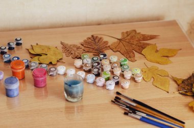 Kurumuş yapraklar, masadaki boya ve fırçalar. Boş zaman, ev zamanı. Seçici Odaklanma.