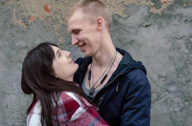 Genç ve mutlu bir çift kucaklaşıyor. Adam genç kadına sıkıca sarılıyor, onu kendine yakın tutuyor. Dişi, erkeğin gözlerinin içine bakar. Yan görüş. Dışarı çıkın. Genç aile.