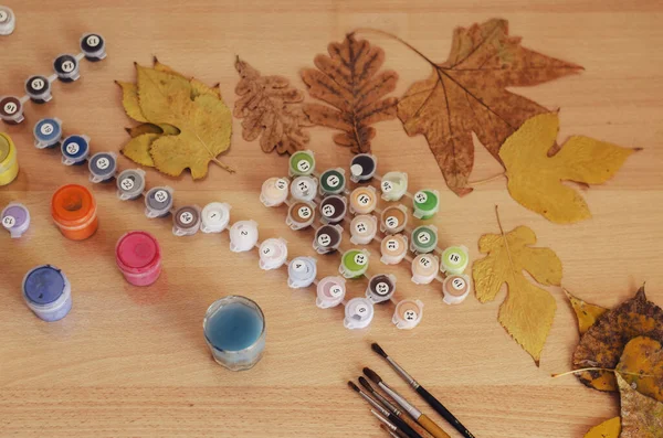 Sarı ve kahverengi yapraklar, masanın üzerine boyamak için akrilik boya ve fırçalar. Boş zaman, ev zamanı aktiviteleri. Seçici Odaklanma.