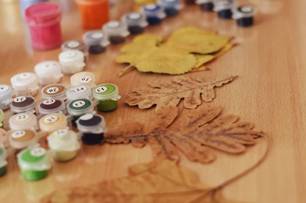 Sarı ve kahverengi yapraklar, masanın üzerine boyamak için akrilik boya ve fırçalar. Boş zaman, ev zamanı aktiviteleri. Seçici Odaklanma.