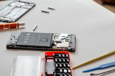 Parçalanmış akıllı telefon, el aletleri ve hafif bir yüzeydeki parçalar. Servis Tamiri. Seçici odak.