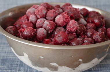Metal bir kasede taze donmuş kırmızı kiraz meyveleri. Buz ve buzla kaplı dutlara yakın çekim. Seçici odak.