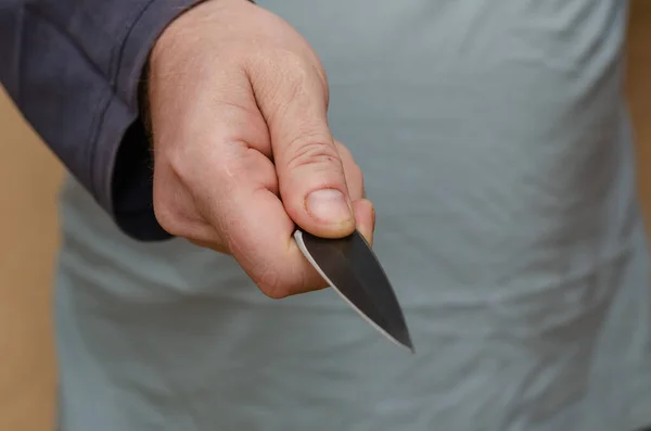 Hand with a knife. Middle section of a man holding a sharp knife. Selective focus.