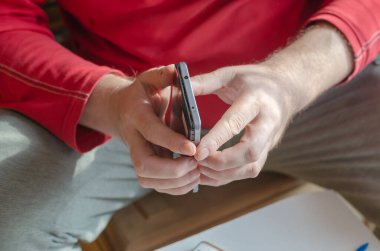 Yetişkin bir erkek akıllı telefonu söküyor. Eller arka koruyucu kapağı ekrandan ayırıyor. Telefon tamiratı ve bakımı. Elektronik atıkları ayıklıyorum. Yakın plan. Seçici odak.