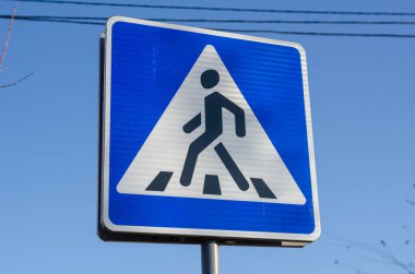 Yaya geçidi tabelası. Mavi gökyüzüne karşı mavi tabela. Gündüz vakti. İnsan yok. Seçici odak.