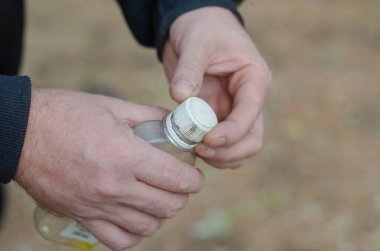 Plastik şişe tutan yetişkin bir adamın iki eli. Sıvı yangın başlatıcı. Seçici bir numara..