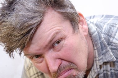 Bir erkek dikizliyor. Dalgalı saçlı bir erkek kameraya bakıyor. Yakın plan. İçeride. Seçici odak.