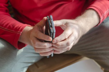 Yetişkin bir erkek akıllı telefonu söküyor. Eller arka koruyucu kapağı ekrandan ayırıyor. Telefon tamiratı ve bakımı. Elektronik atıkları ayıklıyorum. Yakın plan. Seçici odak.