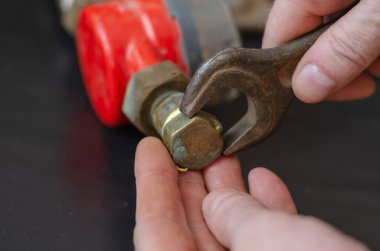 The plumber screws the stopper on the water meter. Red device on a black background. Close-up. Selective focus. No people.