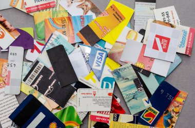 Group of shredded credit cards, business cards and discount cards against a gray background. Pieces of payment cards from various banks. Selective focus. Kiev, Ukraine - 01 05 2022.