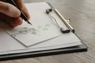 Yetişkin bir erkek eli kağıda yeşil balonlu bir kız çizer. Beyaz bir kağıt üzerine kalemle nokta çizimi. Çağdaş sanat. Seçici odak.