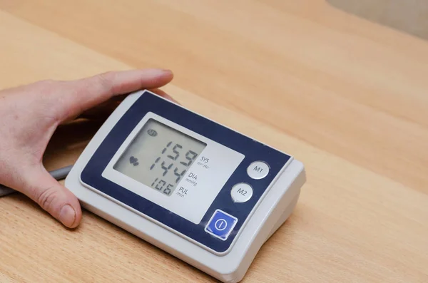 Man Hand Holds Digital Blood Pressure Monitor Table High Blood — Stock Photo, Image