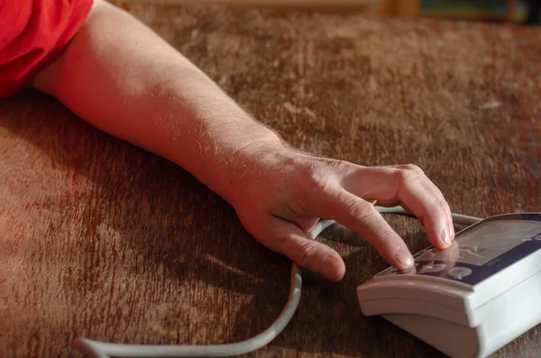 남자의 디지털 모니터의 버튼을 누르고 있습니다 나무판에서 혈압을 측정하는 안으로 — 스톡 사진