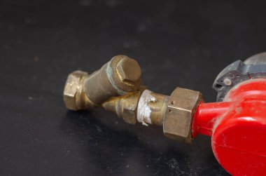 Siyah arka plana karşı tozlu bir su sayacı. Su kaynağının içinden geçen kaba su filtresi olan kırmızı bir cihaz. Seçici odaklanma. Kimse yok..