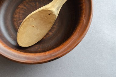 Kahverengi toprak kap ve gri arka planda saçmalar. Ahşap kaşık oymak için boş bir kase ve bir kaşık. Seçici odak.