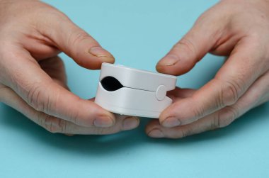 İki adamın elinde nabız oksimetresi var. Kılcal kan oksijeni doygunluğunu ölçmek için tıbbi izleme cihazı olan yetişkin bir erkek. Seçici odak.