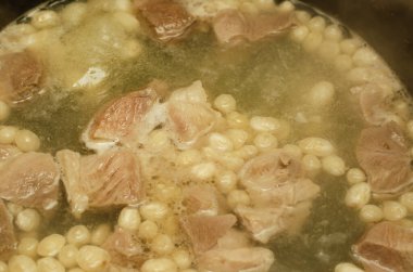 Etli ve fasulyeli çorba pişirmek. Et parçaları ve beyaz fasulyeler kaynar suda kaynatılır. Çorbayı tencereye yakın çekim. Seçici odak.