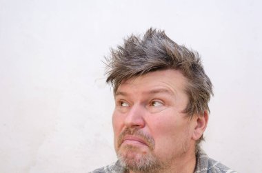 Dağınık bir adam kameranın arkasına bakıyor. Saçları birbirine dolanmış, tıraşsız bir erkek. Odanın içinde. Seçici odak.