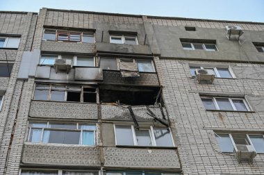 Bir apartmanda sönmüş bir yangın. Kırık camları olan yanmış bir balkon. Duvarlarda siyah is var. Yangın hasarı ve yaralanma. İnsan yok. Seçici odak.