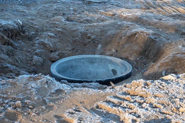 冻土中水井的混凝土环状物 在挖掘出来的洞里有一个铁 混凝土产品 土壤的顶层被霜冻覆盖着 — 图库照片
