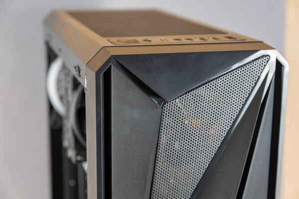 The front of a modern desktop computer. Black system unit in a geometric futuristic design. Digital technology. Close-up. Selective focus