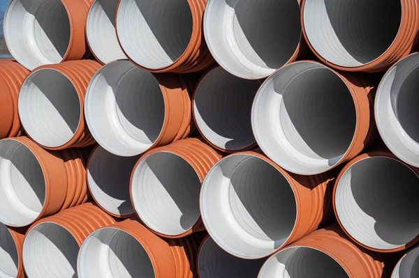 Close-up Stack of new orange polypropylene pipes. Plastic pipes for laying in the gutter.