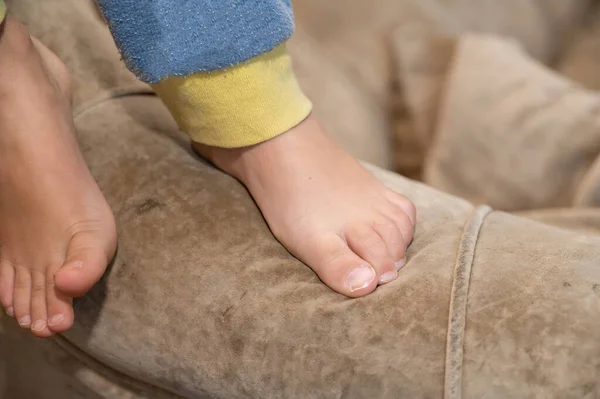 Close-up of a child\'s bare feet. The 5-year-old grandson has just woken up and is standing on the armrest of the couch.