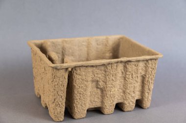 Bastırılmış kartondan yapılmış boş kahverengi bir kap. Gri arkaplana karşı mühür veya geri dönüşüm tepsisi.