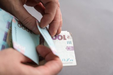 Erkeklerin para saydığı yakın plan çekimler. Yetişkin bir erkek Ukrayna banknotlarını sayar. 1000 hryvniadan oluşan nakit para. Seçici odak.