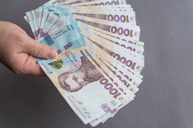 Elinde para tutan bir kadının yakın çekimi. Ukrayna banknotları tutan yetişkin bir kadın. Nakit olarak 1000 Hryvnia. Seçici odak.