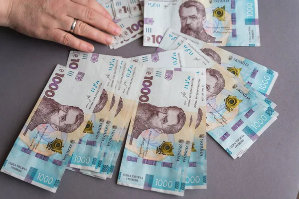 一只在灰色背景下数钱的女手的特写镜头 持有乌克兰钞票的成年女性 面额为1000格里夫尼亚的现金 有选择的重点 — 图库照片
