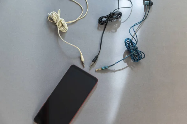 Smartphone Και Ενσύρματα Ακουστικά Φόντο Γκρι Φόντο Πολύχρωμα Ακουστικά Φιλοδοξούν — Φωτογραφία Αρχείου