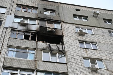 Bir apartmanda sönmüş bir yangın. Kırık camları olan yanmış bir balkon. Duvarlarda siyah is var. Yangın hasarı ve yaralanma. İnsan yok. Seçici odak.