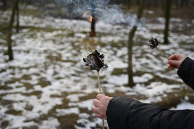 Kış parkının önünde yanan kağıt bir çiçek tutan bir kadın eli. Origami gülü yüz dolarlık banknotlardan yapılmış. Yan görüş. Seçici odak.