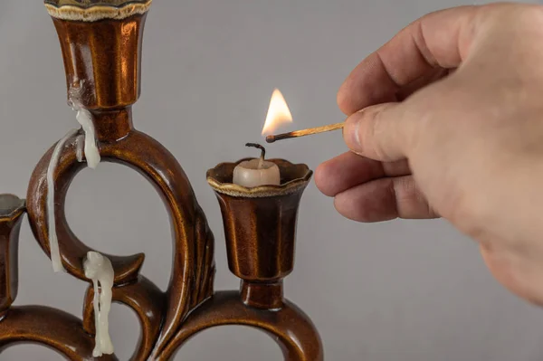 Ręka Mężczyzny Zapala Świece Świeczniku Gorącą Zapałką Brązowy Ceramiczny Świecznik — Zdjęcie stockowe
