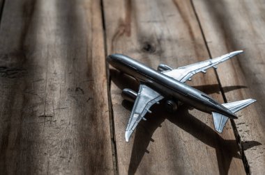 Tahta arka planda gümüş oyuncak uçak. Sert, çatlak tahtalar. Doğal ışıklandırma.