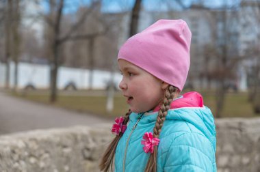 Yaramazlık derecesinde mutlu bir kızın portresi. At kuyruğu örgülü, uzun saçlı beş yaşında bir çocuk..