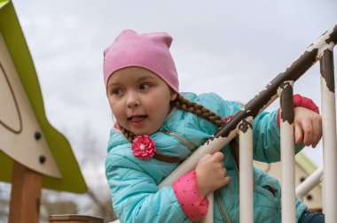 Uzun at kuyruklu ilgili bir kızın portresi. Beş yaşında bir çocuk oyun parkında dünya umurunda olmadan oynuyor..