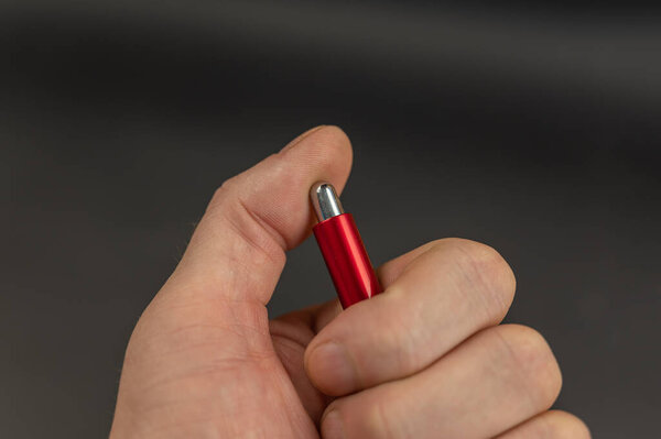 Close-up of a man's hand pressing a ballpoint pen button. The thumb of the left hand nervously presses the button.