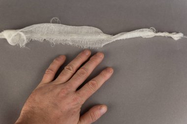 Olgun bir adamın eli ve gri arka planda bir parça beyaz bandaj. Sağlık ve Tıp. Yukarıdan açılı görünüm.