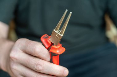 Yuvarlak pense tutan olgun bir adamın eli. Düz yüzey bitiş ve çapı uçlara doğru incelen el bilgisayarı çilingir aracı.