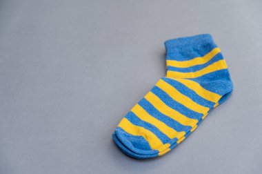 Gri arka plana karşı mavi ve sarı çoraplar. Bir çift parlak renkli çizgili çorap.