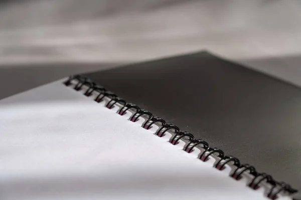 灰色背景下的黑色弹性体笔记本 打开的笔记本和空白白纸的特写 — 图库照片