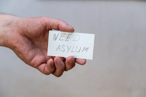Need Asylum Words Written Jagged Letters Man Hand Holds White — Stock fotografie