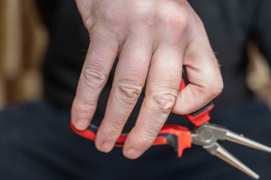 Yuvarlak pense tutan olgun bir adamın eli. Düz yüzey bitiş ve çapı uçlara doğru incelen el bilgisayarı çilingir aracı.