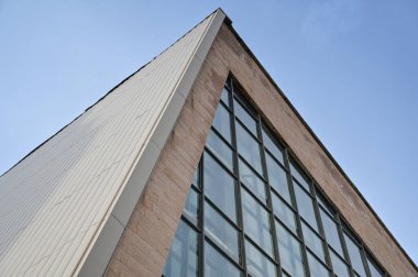 Mavi bulutsuz gökyüzüne karşı cam ve betonun geometrik bileşimi. Birçok dikdörtgen pencereli modern bir bina. Mimarlık. Seçici odak.