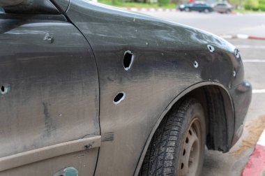 Otoparktaki şarapnelden delik deşik olmuş bir yolcu vagonu. Ukrayna 'daki savaş sırasında hasar görmüş bir sedan. Sivil misket mühimmatlarının bombalanmasının sonuçları .