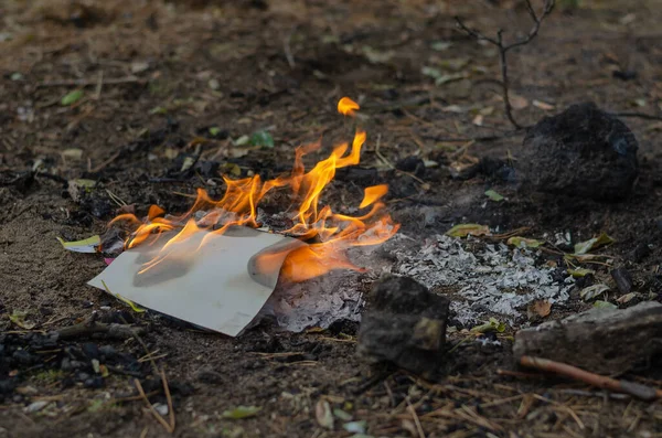 Yırtık bir defterin ateşinde yanıyor. Kapak ve çok renkli çarşaflar gri küle dönüşüyor. Odanın dışında. Seçici Odaklanma.